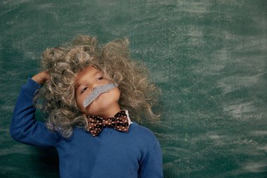 Yeşil karatahtaya karşı neşeli gülümseyen küçük çocuk. Kameraya bakıyorum. Biraz Einstein tarzı. Okul kavramı