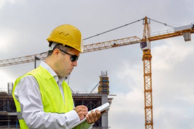 Güvenlik kaskı ve yeleği olan inşaat işçisi inşaat alanında çalışıyor. Endüstriyel alanda çalışan insanlar kavramı