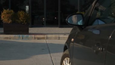 Adam gri arabasıyla geliyor, arabayı park ediyor, arabayla seyahat ediyor.