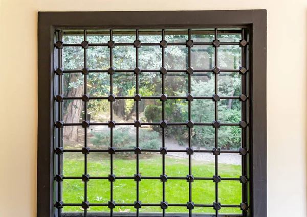 Iron barred home glass window and back to garden green grass