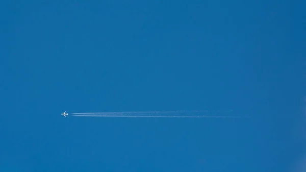 Ein entferntes Flugzeug, das einen horizontalen Dampfschweif verlässt — Stockfoto