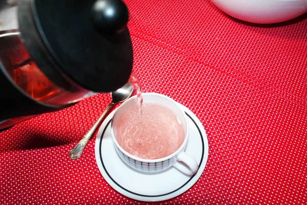 赤の背景にお茶 ソーサー スプーンでカップ — ストック写真