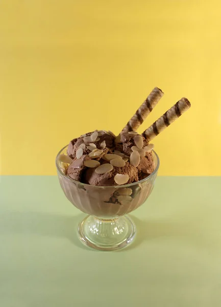 Chocolate ice cream with nuts, candies and cookies on a colored background.