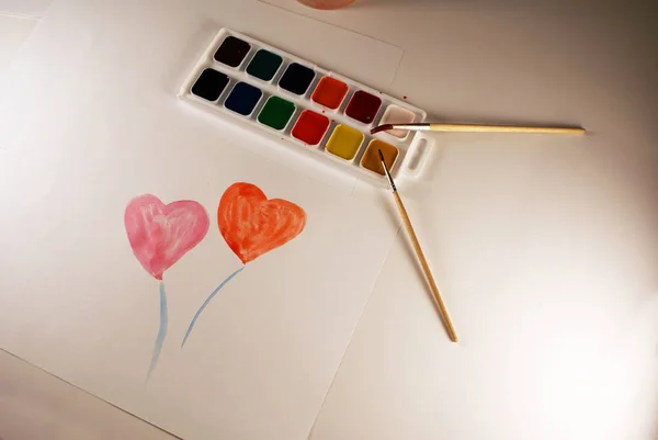 A palette of watercolors and brushes, accessories for the artist, heart.