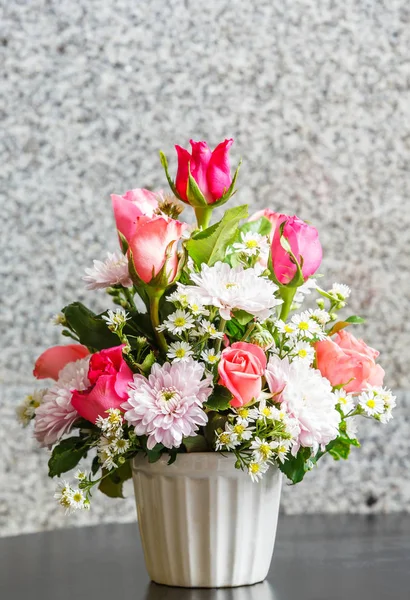 Close up rose and chrysanthemum flower bouquet in glass vase on wooden table