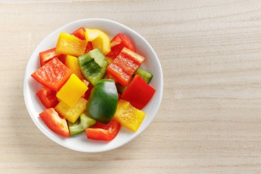 Doğranmış yeşil ve sarı kırmızı tatlı biber Ahşap doğrama tahtası üzerinde seramik tabak kapatın