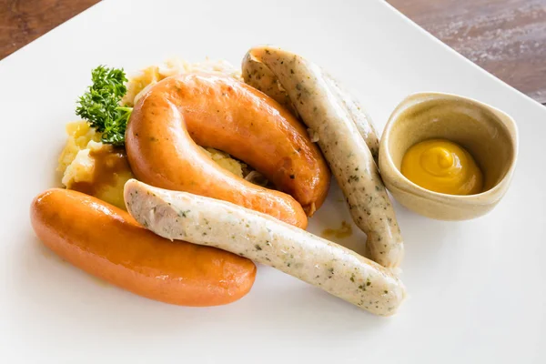 Grilled german sausages served with sauerkraut, mashed potato and mustard