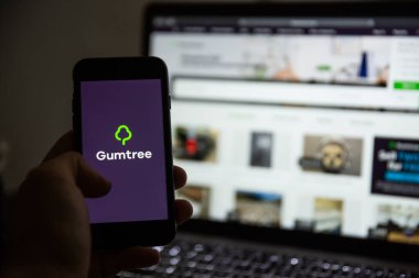 TERNOPIL, UKRAINE - JANUARY 11, 2020: Man holds Apple iPhone 7 with GumTree brand logo on its screen in the evening. GumTree is a global sales platform.
