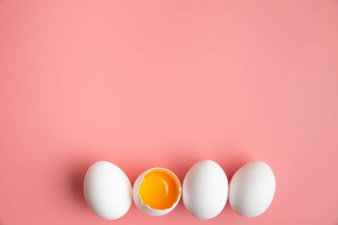 Beyaz tavuk yumurtası ve pastel pembe arka planda yumurta sarısı. Paskalya bayramı konsepti. Biri açık. Farklılık fikri.