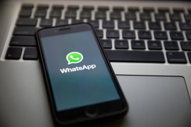 TERNOPIL, UKRAINE - JANUARY 11, 2020: WhatsApp brand logo in corporate colors on the screen of Apple iPhone 7 in the evening. Keyboard of Macbook Pro in background. WhatsApp is a popular messaging application.
