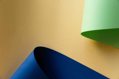 Açık yeşil, neo nane ve koyu mavi, lacivert kağıtlar altın zeminde yaratıcı kıvrımlarda bükülür. Soyut moda minimalist stil geometrik tasarım.