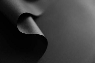 Karanlık tek renkli arka planda kıvrık kağıt kenarlı parlak bir dalga. Yaratıcı moda minimalist tarzı arka plan.