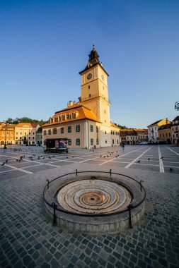 Şehir merkezi meydanı (Piata Sfatului) ile belediye meclisi kulesi sabah güneşinin doğuşu manzaralı, Brasov, Transilvanya, Romanya. Meşhur seyahat yeri yaz dikey kartpostalları.