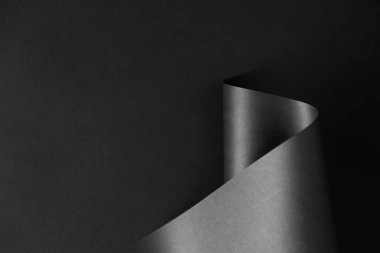 Koyu arkaplanda parlak siyah monokrom kağıt dalgası. Geometrik minimalist biçim arkaplanı.
