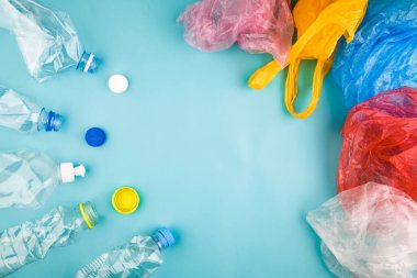 Renkli plastik şişeler, kapaklar, mavi arka planda çantalar. Kopya, metin ve harfler için boş alan. Plastik koleksiyon poster konsept şablonu.
