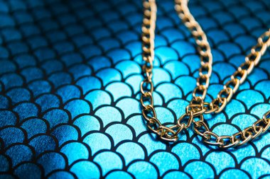 Derin mavi yansıtıcı ölçekte parlak, büyük bir zincir aksesuarı, kusursuz desenli kumaş. Moda tasarımı kavramı. 