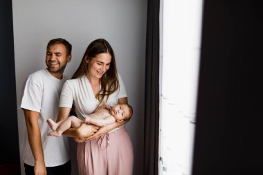 Duygusal olarak mutlu, gülen ebeveynler küçük bebeklerini kucağında tutuyorlar. Rastgele bir sahne. Kopya için boşluk, metin için oda.