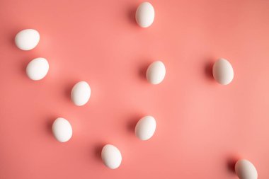 Beyaz organik tavuk yumurtaları ve basit pastel pembe mutfak masası arka plan manzarası. Yaratıcı trend minimalist düz paskalya konsepti.