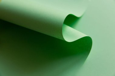 Açık yeşil eğrinin soyut yaratıcı tasarımı düz arkaplanda kağıt şeklinde. Tek renkli geometrik moda posteri. Kopyalama, metin ve harf için boş boşluk.