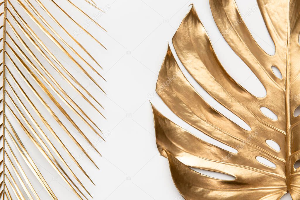 Big spray painted golden palm and monstera leaves on clean white background. Empty space, room for text. Luxury minimalist style artistic creative fashionable concept idea. Cosmetics banner template.