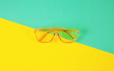 Soyut renkli kağıttan arka planda sarı renkli güneş gözlüğü. Minimal yaz geliyor..