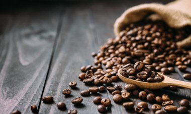 Tahta masaya kahve çekirdekleri serpiştirilmiş jüt çanta. Klasik konsept. Makarayı kopyala. Seçici olarak kaşığa odaklan. Yakın görünüm.