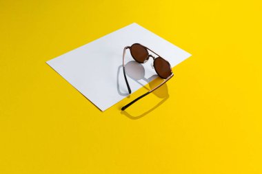 Beyaz ve sarı soyut arka planda izole edilmiş kahverengi uniseks klas güneş gözlükleri. Uzayı kopyala Moda erkek aksesuar konsepti.