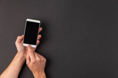 Siyah arka planda beyaz akıllı telefon ve boş ekran tutan mankafalar. Mesaj için yer var. Düz yatıyordu.