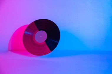Soyut arkaplanda renkli mor neon ışıkla aydınlatılmış siyah LP vinil disk. Uzayı kopyala En düşük elektronik müzik gecesi parti yaratıcı konsepti.