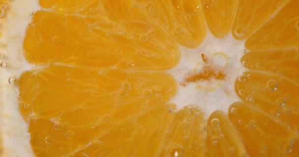 Kousek čerstvé pomeranče pod vodou se vzduchovými bublinami.