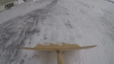 Şehirdeki bir konutta kaldırımdan kar temizliyorum.