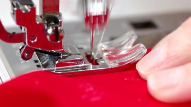 Dikiş makinesine kırmızı kumaş dikiyorum.