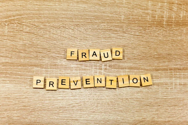The words \'Fraud Prevention\' on a wooden background