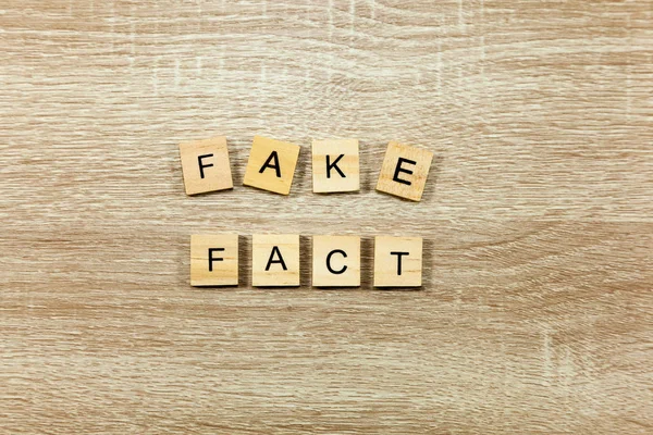 The words \'Fake\' and \'Fact\' on a wooden background