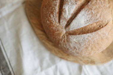 Beyaz bir masa örtüsünün üzerinde bir somun ekmek.