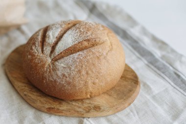 Beyaz bir masa örtüsünün üzerinde bir somun ekmek.