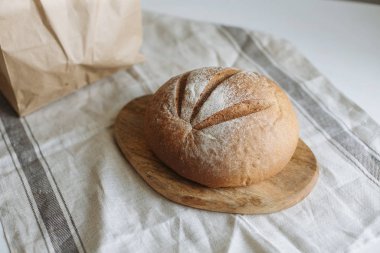 Beyaz bir masa örtüsünün üzerinde bir somun ekmek.