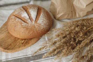 Beyaz bir masa örtüsünün üzerinde bir somun ekmek.