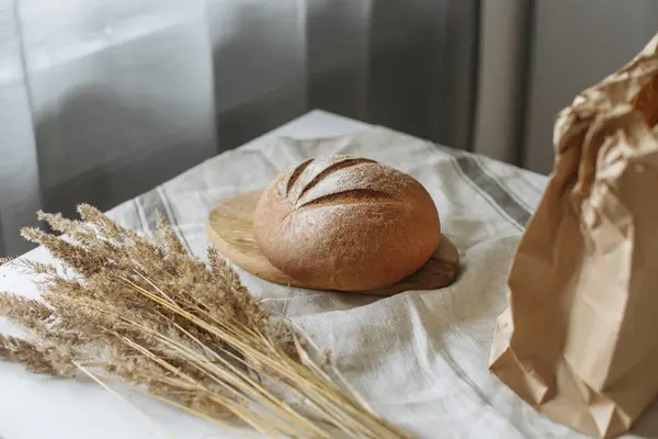 Beyaz bir masa örtüsünün üzerinde bir somun ekmek.