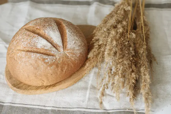 Beyaz bir masa örtüsünün üzerinde bir somun ekmek.