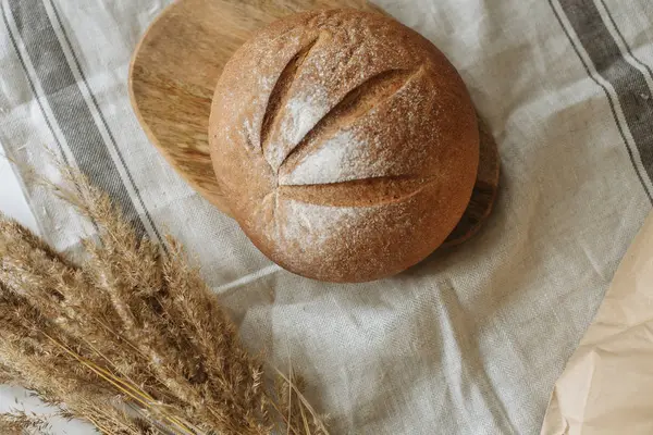 Beyaz bir masa örtüsünün üzerinde bir somun ekmek.