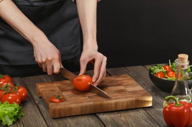 Kadın taze sağlıklı salata pişiriyor. Tahta masada, üzerinde kopyasal alan olan sebzeleri kesen kadın eller..