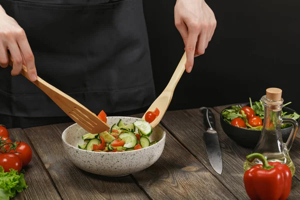 Женщина смешивает свежий овощной салат на деревянном столе. Женские руки с копирайтом . — стоковое фото
