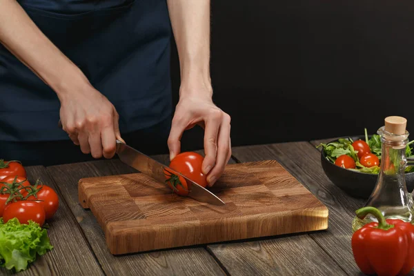 Donna che cucina insalata fresca e sana. Mani femminili che tagliano verdure a bordo su tavolo di legno con copyspace . Foto Stock Royalty Free