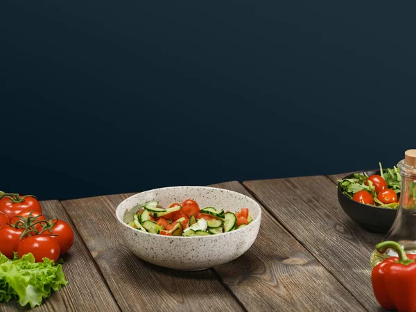 Свежий овощной салат в белой миске на деревянном столе на синем фоне с копирайтом. Здоровый вегетарианский образ жизни . — стоковое фото