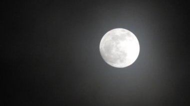 Karanlık bulutlu bir gecede dolunay. Ay 'ın önünden bulutlar geçiyor, gerçek zamanlı çekim. Geceleri bulutlar geçiyor. Geceleyin dolunay ve gerçek zamanlı bulutlar..