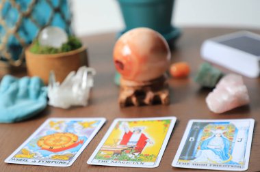 Tarot kartları ahşap bir masanın üzerine serilmiştir. Arka planda kristaller duruyor. Falcılık konsepti. Carneilian küreleri.