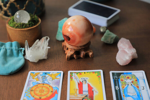 Tarot cards are laid out on a wooden table. Crystals stand in the background. Fortune telling concept, Carneilian spheres.