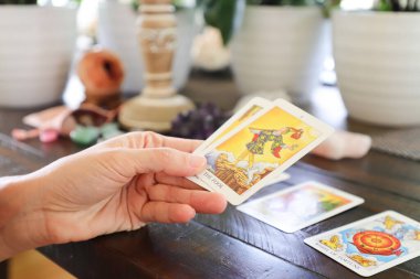 Miami mi? Florida mı? ABD. 27.05.2020 Tarot kartı. Esrarengiz natürmort. Dişi eller, tarot kartlarını ahşap bir masanın üzerine serer. Arka planda, farklı kristaller serilmiştir. sanat odaklı