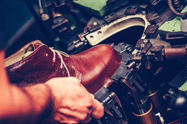 Tecrübeli bir ayakkabıcı ayakkabıları giymekte bir makine kullanıyor.